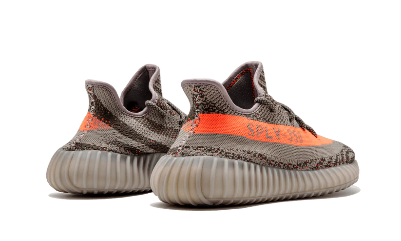 L'Adidas Yeezy Boost 350 V2 "Carbon Beluga" unisce vividi tocchi di colore con un design fantasia. I lacci in corda fissano la tomaia Primeknit traspirante, resa in una finitura grigio scuro con linee nere ondulate e macchioline arancioni a contrasto. Sul lato laterale, una striscia arancione abbinata mostra il marchio "SP
